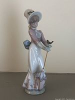 Front and side views of the Lladro Garden Song Girl figurine showing full figure, clothing, parasol, and bird details.