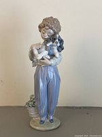 Front view of the Lladro figurine showing full body of the child holding the dog with plant detail at base.