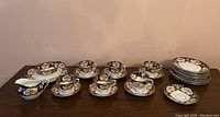 Full view of all items in the fine china set including cups, saucers, creamer, sugar bowl, and plates.