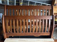 Photo showing the headboard and footboard of the disassembled solid wood queen sleigh bed in classic style, including the curved top edges and slatted wood design.