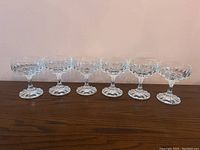 Front view of all six Villeroy & Boch crystal sherbert glasses lined up on a wooden surface.