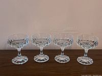 Set of four Villeroy & Boch crystal sherbet glasses shown in clear detailed view on wood surface against plain background.