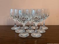 Nine crystal wine glasses arranged in triangular formation on wooden surface