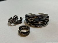 Three-piece set arranged on white background showing cuff, ring and earrings