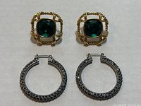 Photo showing both pairs of earrings: gold-tone square green stone earrings on top and silver-tone pavé crystal hoop earrings below.
