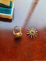 Ring and brooch together on wooden surface with partial jewelry box visible