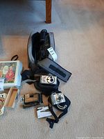 Lot of three cameras displayed on carpet: Canon PowerShot A560, Sanyo digital camera, and Pantages Theatre Toronto camera with cases and original box.