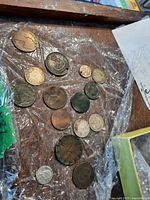 Top view of 15 assorted collectible coins wrapped in clear plastic on wooden surface