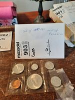 Photo showing six 1967 Canadian coins sealed in mint packaging with a label indicating 'set of 1967 mint set Canadian' on the back