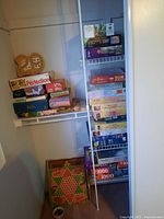 Photo of two shelves holding stacked board games including Perfection, Spill and Spell, and Yahtzee.