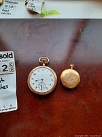 Two pocket watches side by side showing full front view and relative size