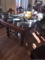 Full view of wooden dining table covered with dishes on top showing size and style