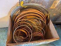 Box filled with multiple wood and metal crafting hoops of varying sizes.
