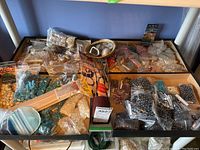 Full shelf view showing multiple resealable baggies of various bead types laid out on a low table beneath a white shelving unit