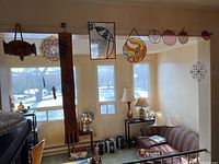 Wide view of hanging stained glass pieces including fish shape, circle designs, and various bead art pieces along a wall above a living space