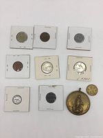 All 10 items laid out showing 9 coins in holders and 1 large medallion.