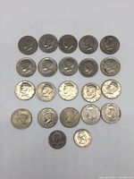 Front (obverse) view of 22 US collectible coins consisting of 20 Kennedy Liberty Half Dollars and 2 Susan B Anthony One Dollar coins showing the profiles and condition.