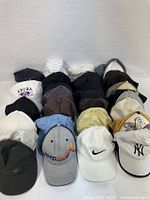 28 assorted baseball and trucker caps in multiple rows showing overall variety and color range