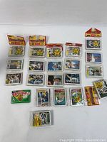 Top-down view of multiple unopened packs and loose vintage MLB baseball cards laid out on a white surface.