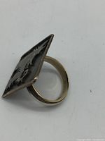 Side profile of ring showing band and plaque orientation