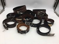 Photo showing multiple rolled belts in black and brown with metal buckles of rectangular and decorative styles