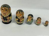 Full set of 5 nesting dolls lined up by size showing detailed folk art painting and varnish.