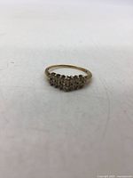 Front view showing cluster of round diamonds set in yellow gold band.