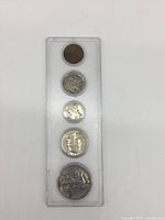 Top view of 5 US collectible coins in plastic holder showing obverse sides including Buffalo nickel and Mercury dime.