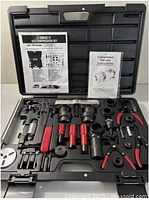 Full view of the SPX Kent-Moore A/C compressor kit open in plastic case showing all tools and manuals inside.