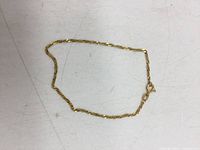 Full view of the 7-inch twist pattern gold bracelet laid flat on a surface.