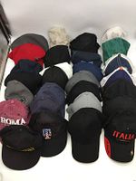 Photo of assorted baseball caps and trucker hats arranged in rows showing front views and logos for some caps.