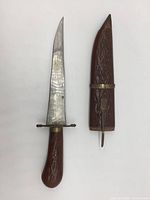 Photo showing the knife with the blade out and the matching carved wooden sheath beside it, highlighting the carved handle and blade shape.