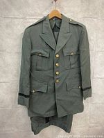 Front view of vintage military pilot jacket hanging on hanger with folded pants beneath
