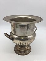 Side view of silver tone vintage champagne chiller with urn shape, pedestal base, and two handles.
