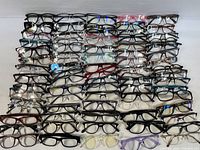 Top view of all eyeglasses and optical frames laid out in rows, showing variety in frame styles, shapes, and colors.