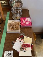 Top view of the earring tree holding multiple pairs of silver-tone sparkly pierced earrings alongside two necklace sets and holiday earrings laid out on a table.