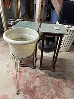 Photo showing two square marble-top flower stands and one white plastic flower pot in a metal stand on a red floor.