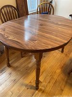 Photo showing the oval wood finish kitchen table with turned legs and visible wood grain.