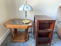 Vintage brass lamp with floral glass shade and two wooden end tables placed next to each other on carpet.