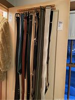 Photo of several men's ties and belts hanging on a rack, showing variety of colors and materials