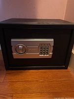 Front view of black steel safe with electronic keypad and handle.