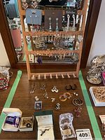 Full view of vintage pierced dangle earrings displayed on wooden stand and wood table including small jewelry boxes and boxed necklace set.