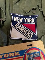 Close-up of green flight suit with sewn New York Rangers patch on the chest area.