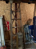 Wood ladder approximately 6 feet tall, vintage solar light fixture installed on decorative metal scrollwork, quartz heater positioned in front of ladder.