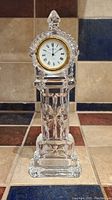 Tall Wittnauer crystal clock shaped like a miniature grandfather clock. Clear cut glass with starburst motifs and gold-tone bezel around white clock face with Roman numerals.