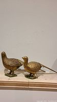 Photo showing both copper bird statues side by side on flat surface