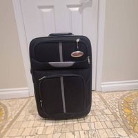 Closed frontal view of black Air Express Classic luggage showing front zippered pockets and brand tag.