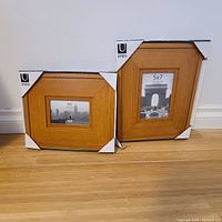 Two wooden picture frames, 4x6 and 5x7 size, with Umbra branding and corner protective covers.