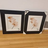 Two black Umbra picture frames shown side by side, one in original packaging, each 11x14 inches with white matting and black framing.