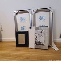 Four picture frames: two large silver Umbra frames each with three blue floral photos, one small black photo frame, and one medium Umbra frame in packaging.